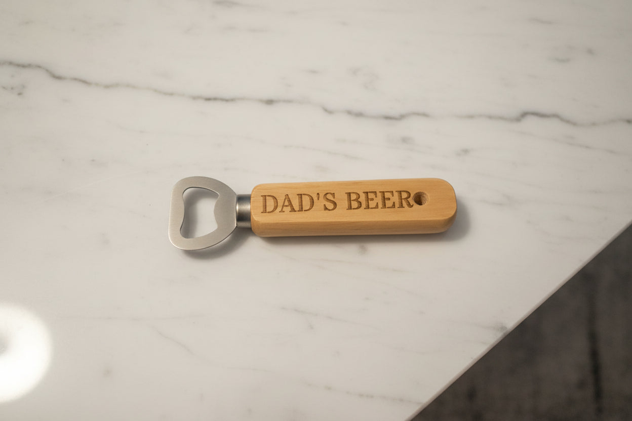 Bottle opener with 'DAD'S BEER' engraving on a wooden surface
