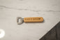 Bottle opener with 'DAD'S BEER' engraving on a wooden surface